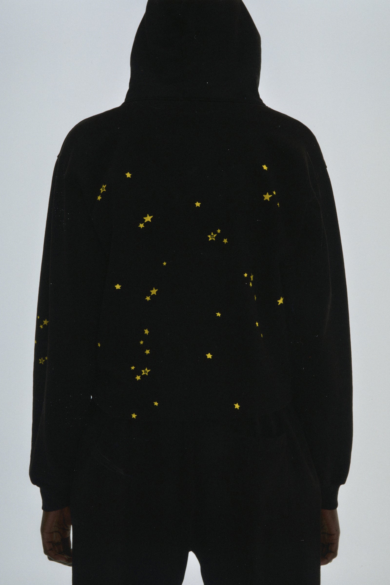Black 100% cotton fleece Atlanta hoodie with scattered yellow star print, rib knit cuffs and hem.