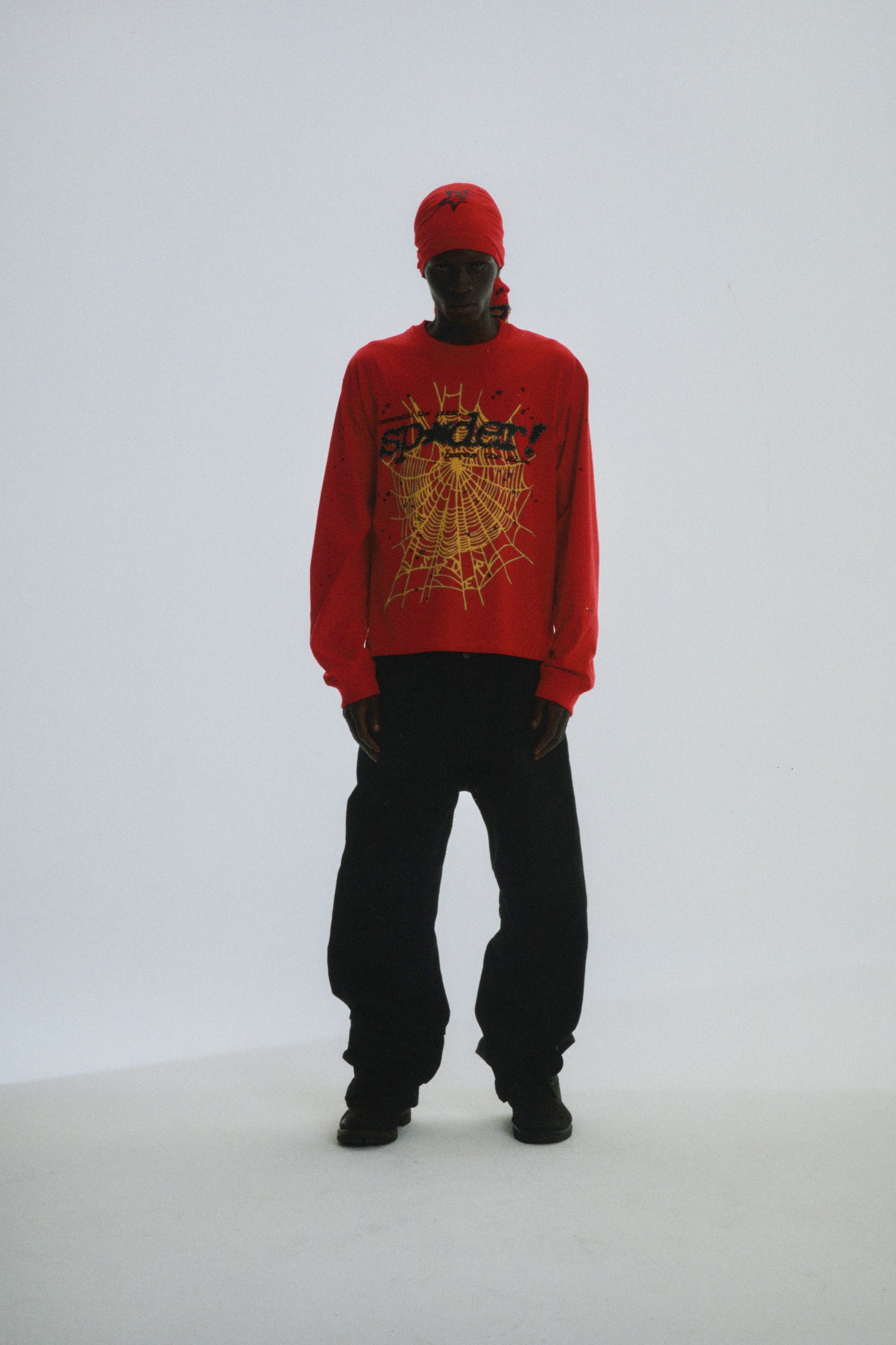 Red PUNK V2 LONGSLEEVE with yellow SP5DER web graphic, worn by a model with black pants.