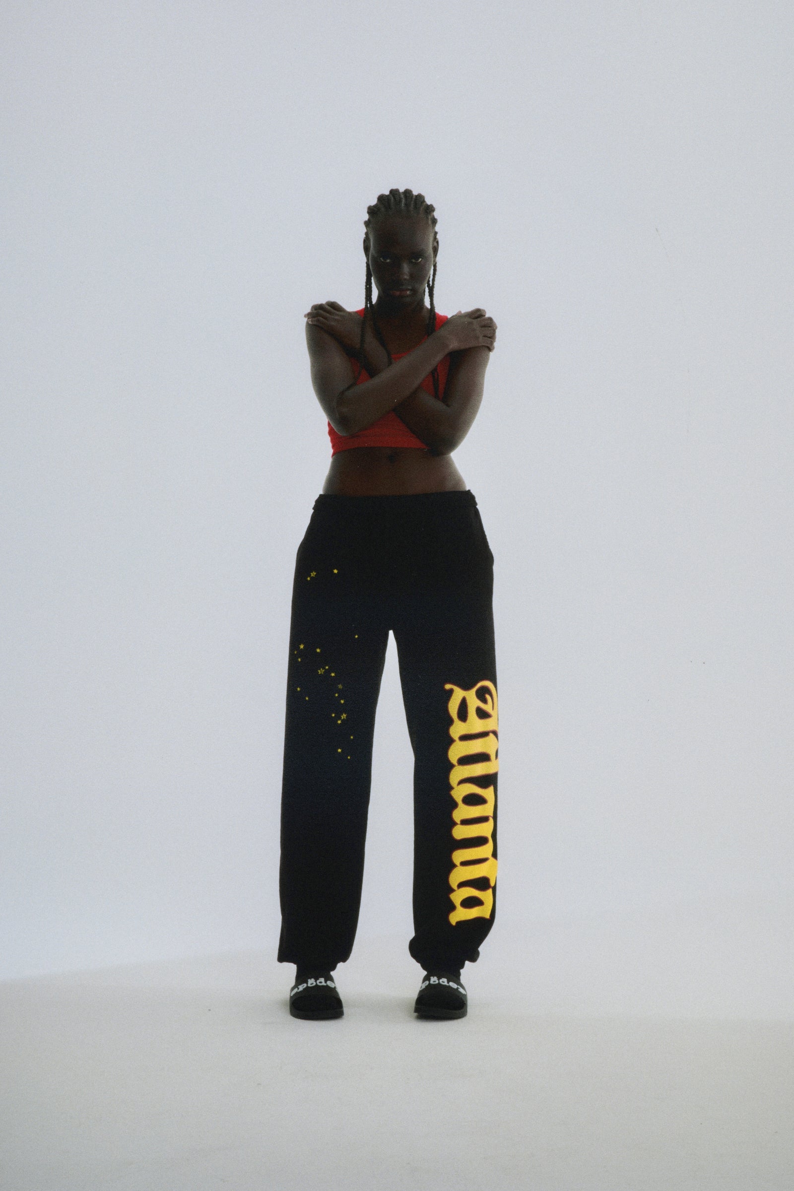 Black Atlanta Sweatpants with yellow script text and scattered stars, worn by a model.