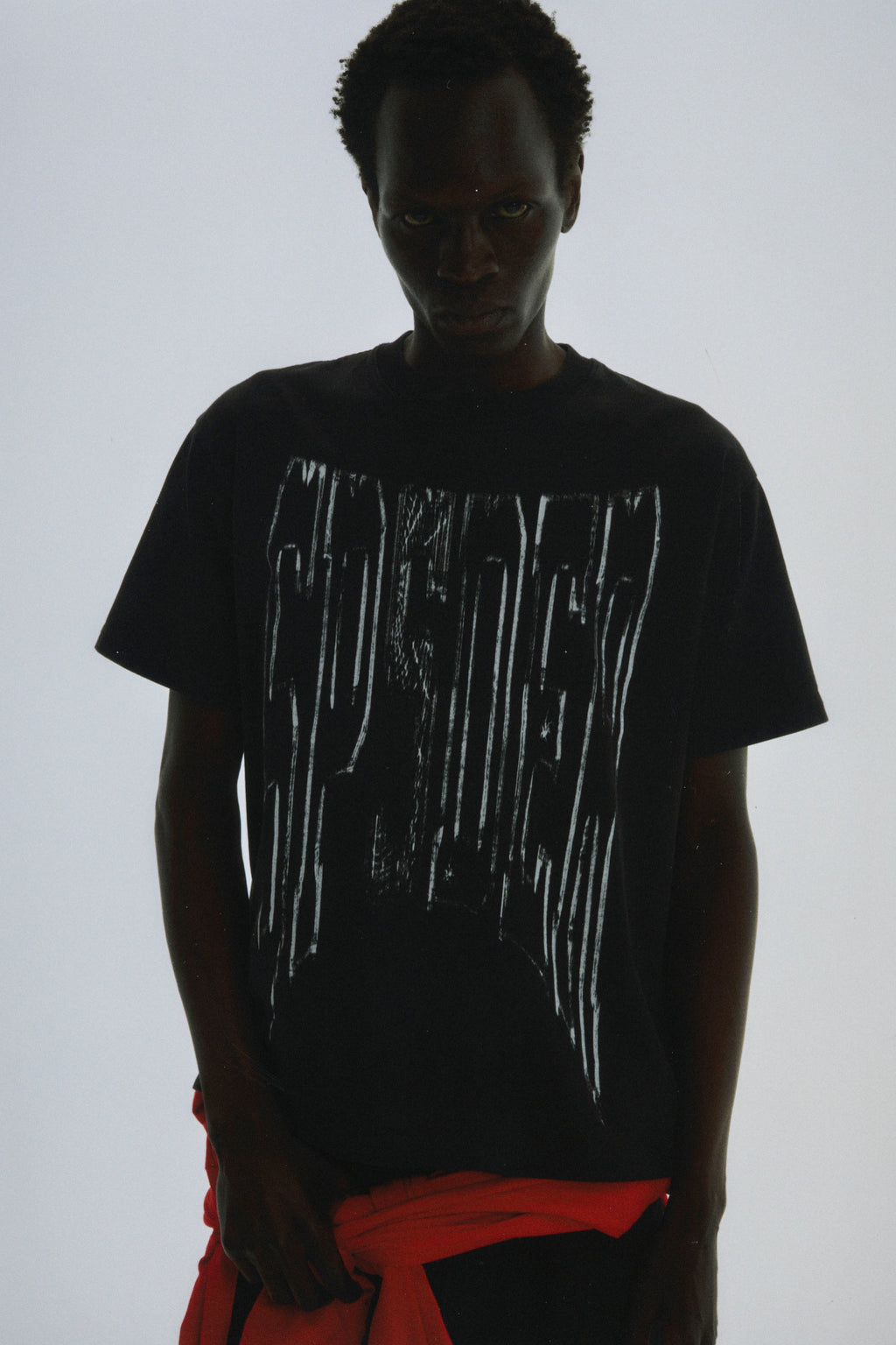 Black 100% cotton tee with white diffused collegiate graphic print on front. Standard fit.