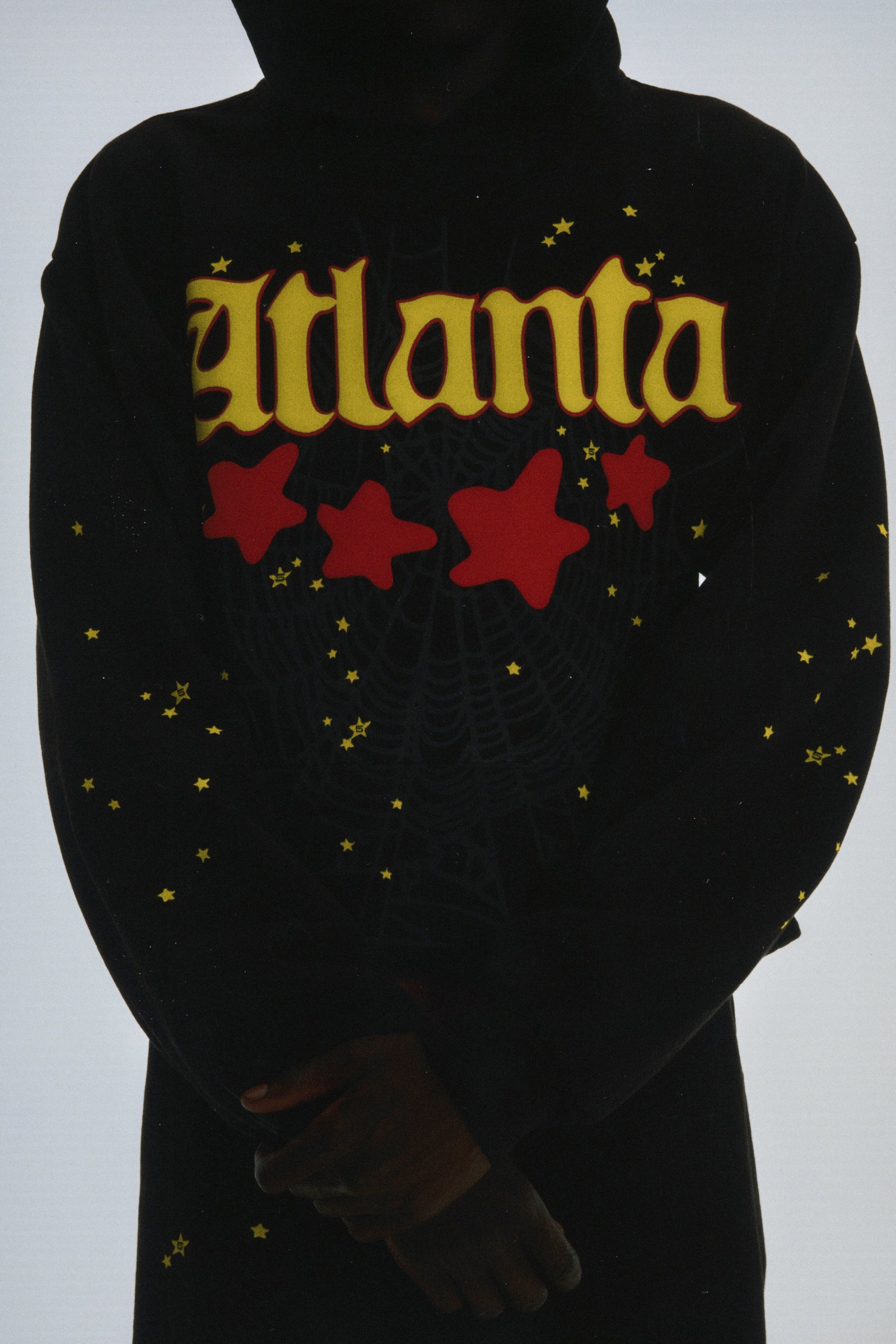Black 13oz cotton fleece Atlanta hoodie with yellow puff print script, red stars, web print, and scattered yellow stars.
