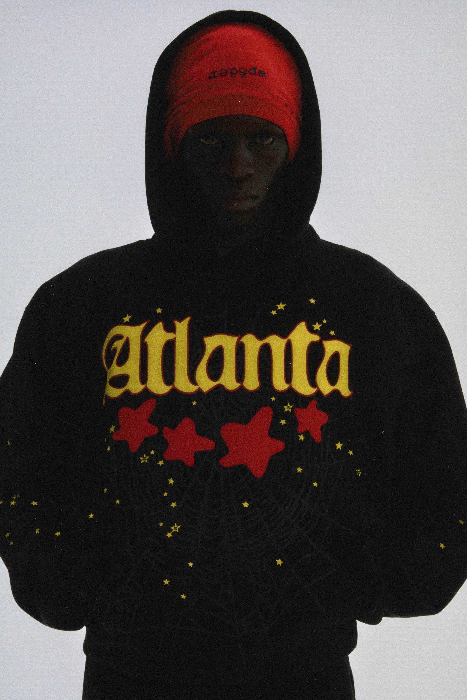 Black 13oz cotton fleece Atlanta hoodie with yellow script, red web, and scattered stars.