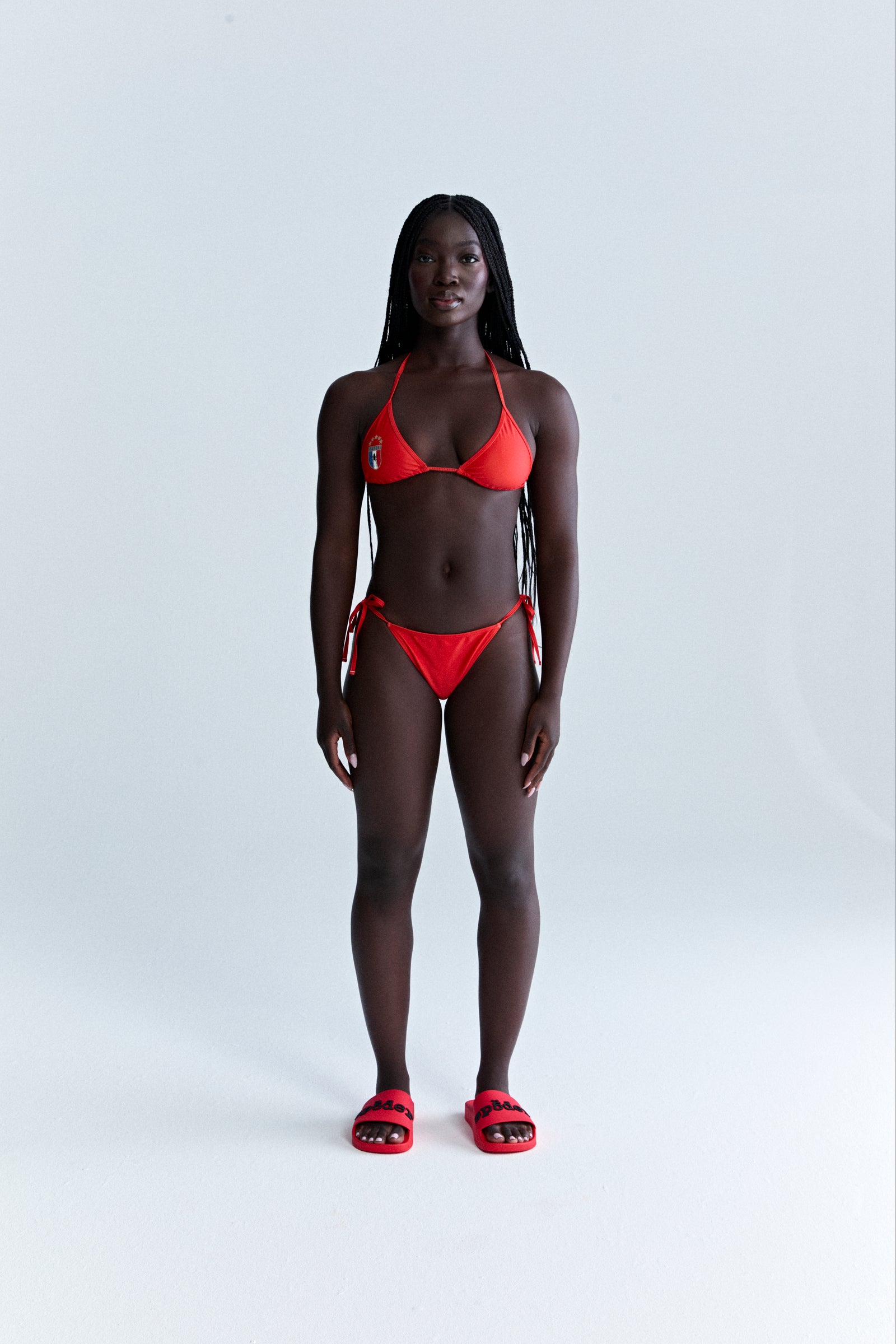 Red stretch nylon jersey ARAIGNÉE bikini set with rope ties, crest graphic, and logo.