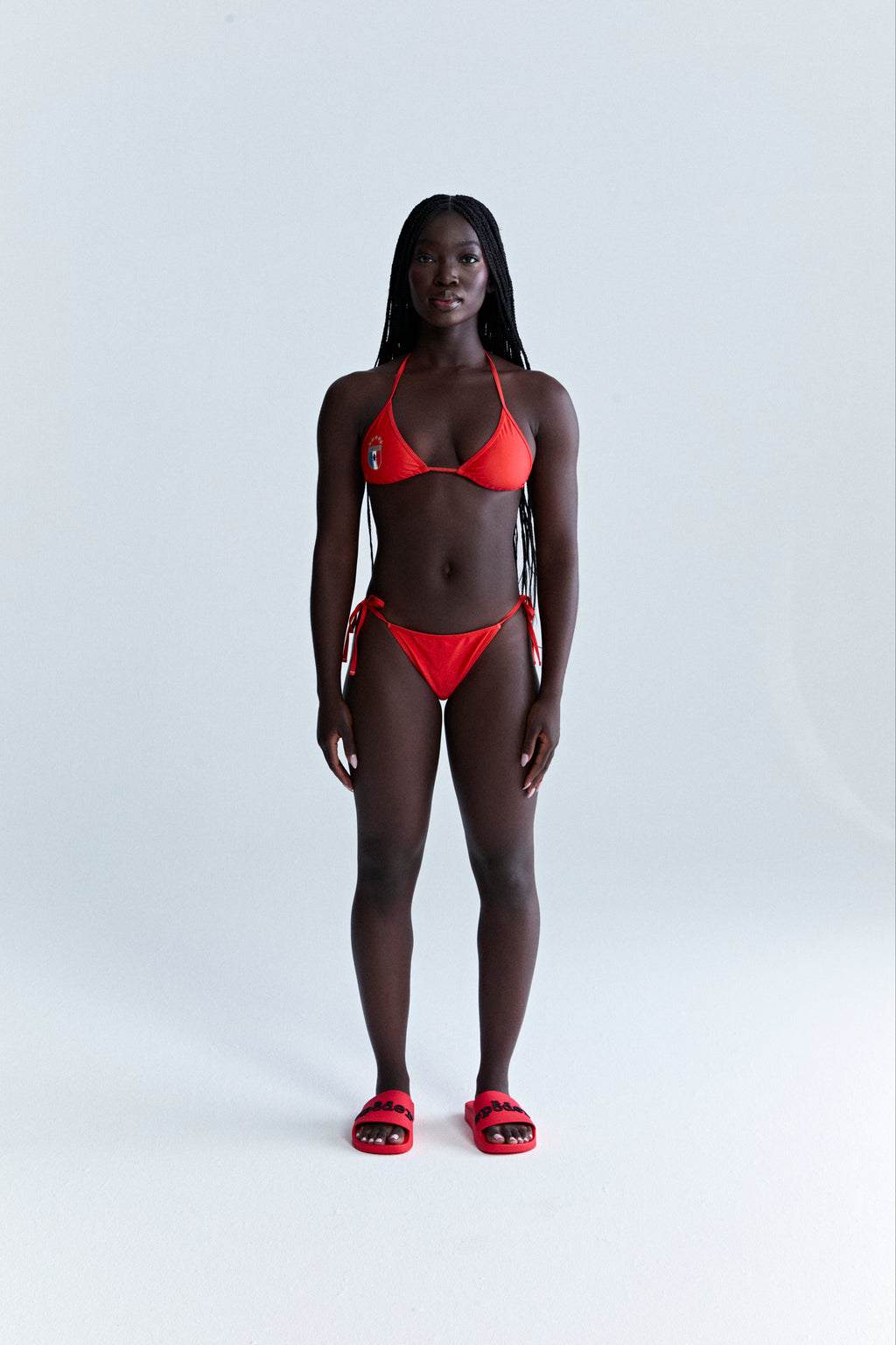 Red stretch nylon jersey ARAIGNÉE bikini set with rope ties, crest graphic, and logo.