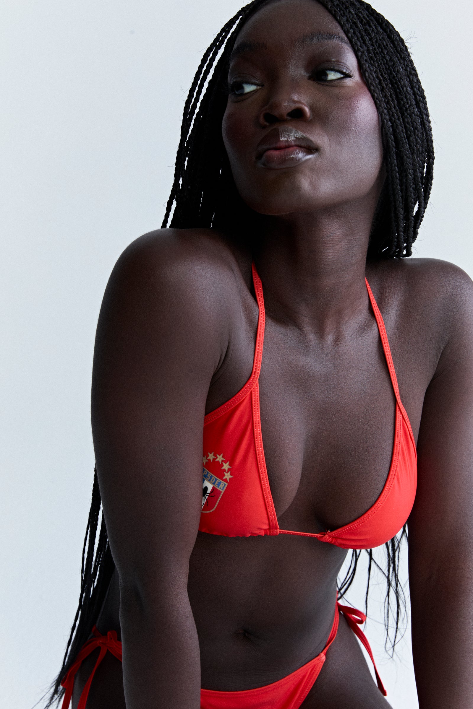 ARAIGNÉE BIKINI: Red stretch nylon jersey triangle top and bottom with rope ties and crest graphic.