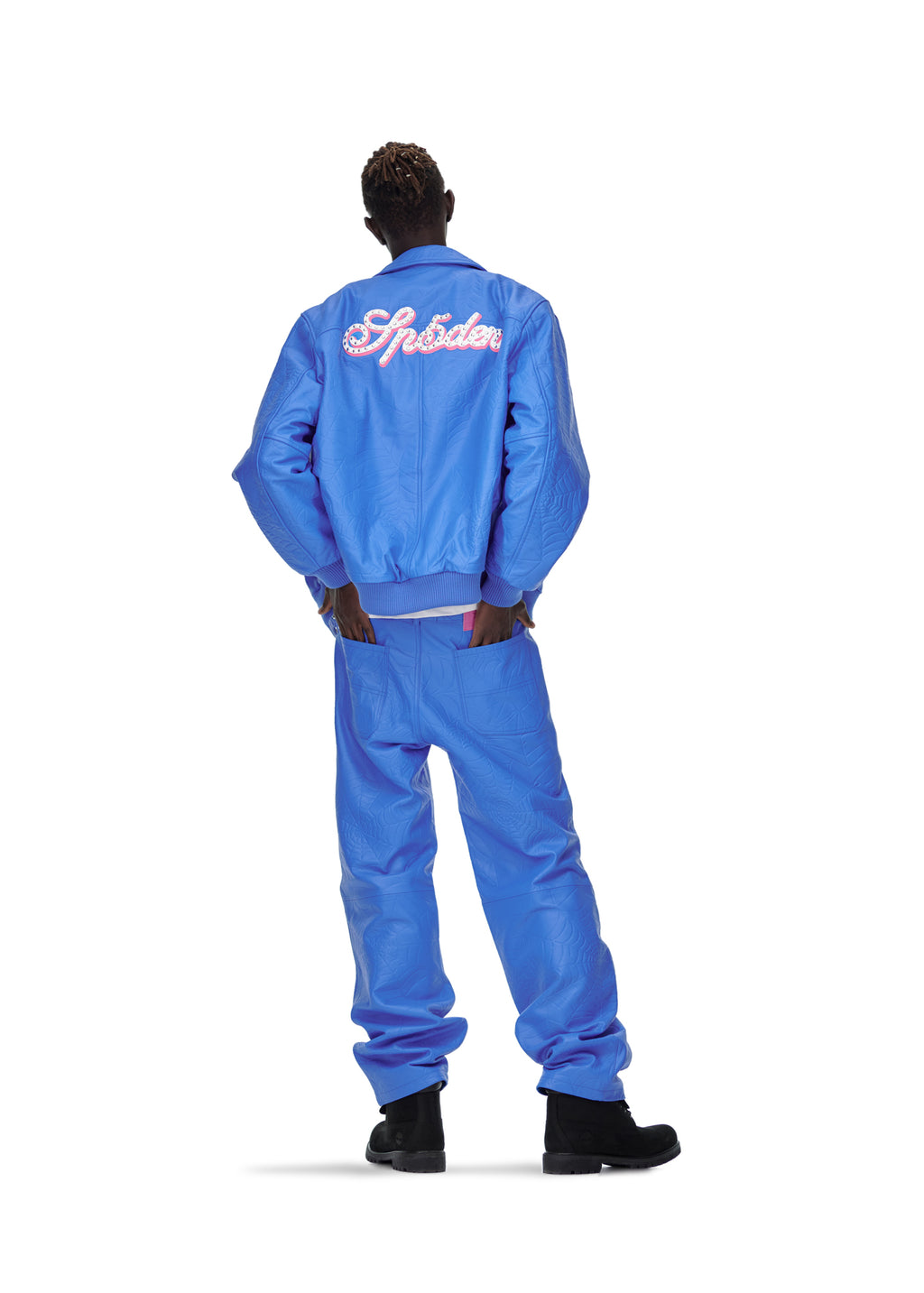 Male model in blue debossed web leather jacket with pink "Spider" text on back, matching pants, and black boots.