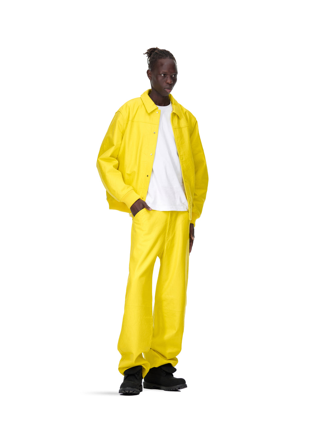 Male model in bright yellow debossed web leather jacket and matching pants, white tee, black boots.