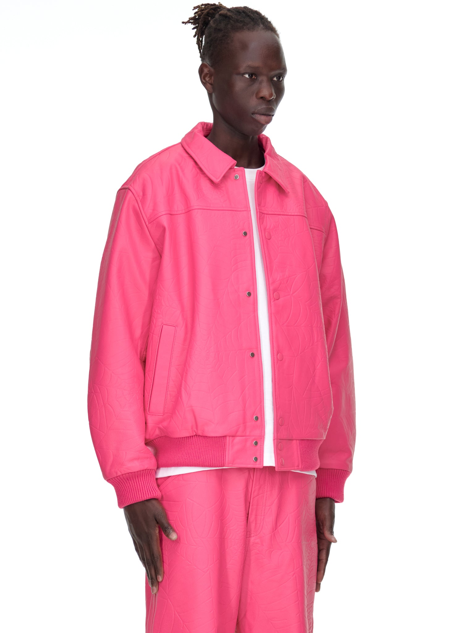 Male model in a pink debossed web cowskin leather jacket with press-stud closure and ribbed trim.