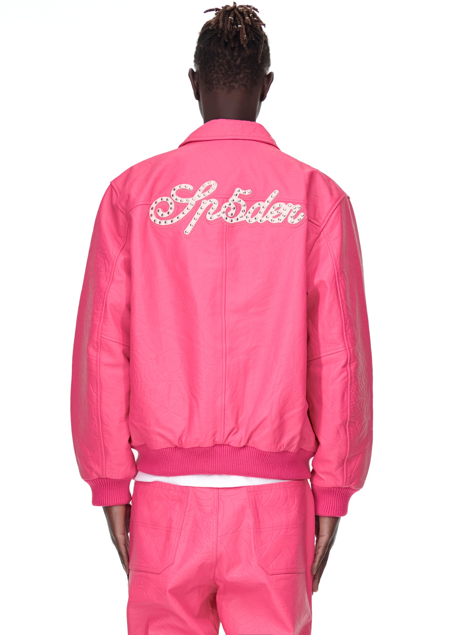 Back of a male model wearing a pink debossed web cowskin leather jacket with studded "Sp5der" text.