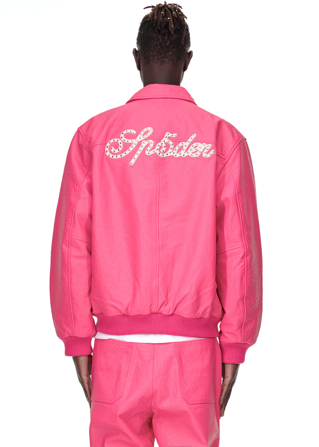 Back of a male model wearing a pink debossed web cowskin leather jacket with studded "Sp5der" text.
