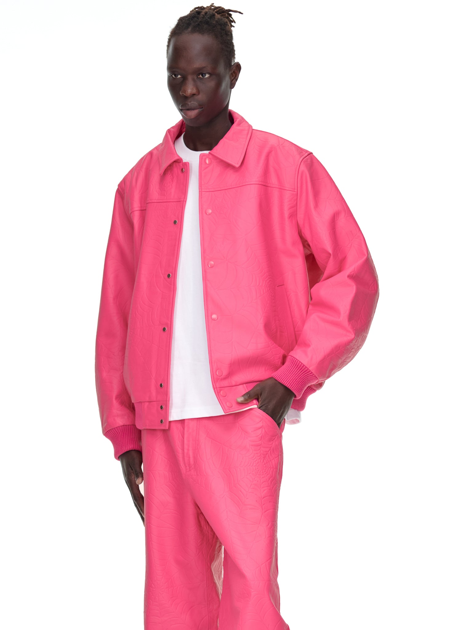 Male model in a pink debossed web leather jacket and matching pants, with a white t-shirt.