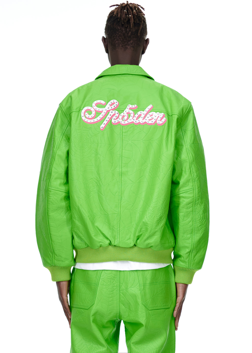 Back of a male model wearing a bright green debossed web cowskin leather jacket with "Sp5der" in pink studs.