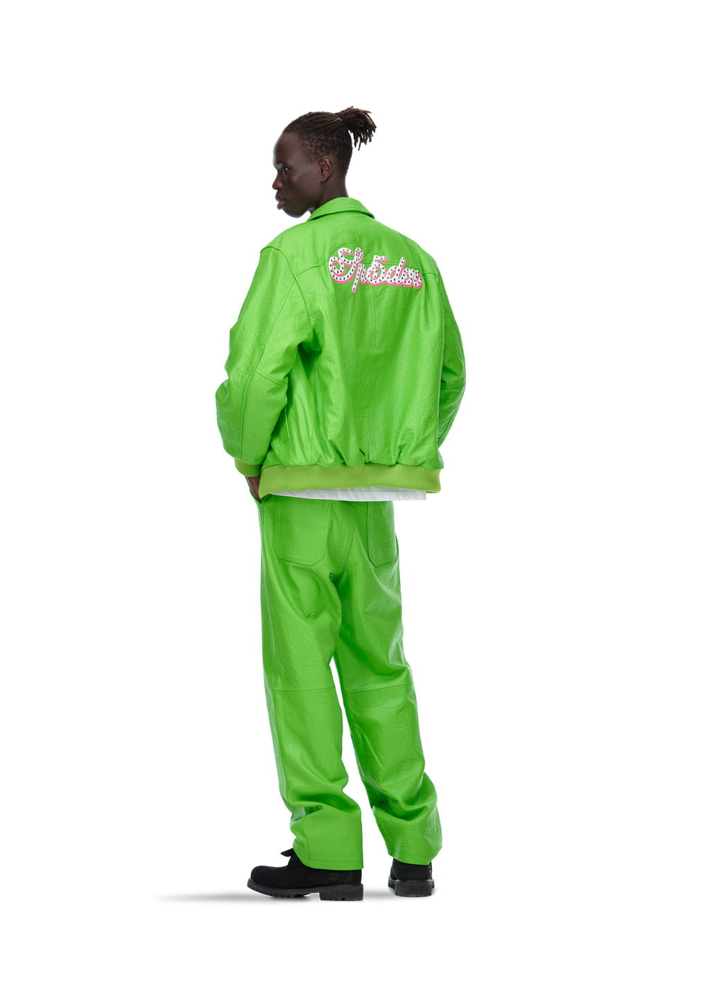 Male model in a bright green debossed web leather jacket with studded text on the back, and matching pants.