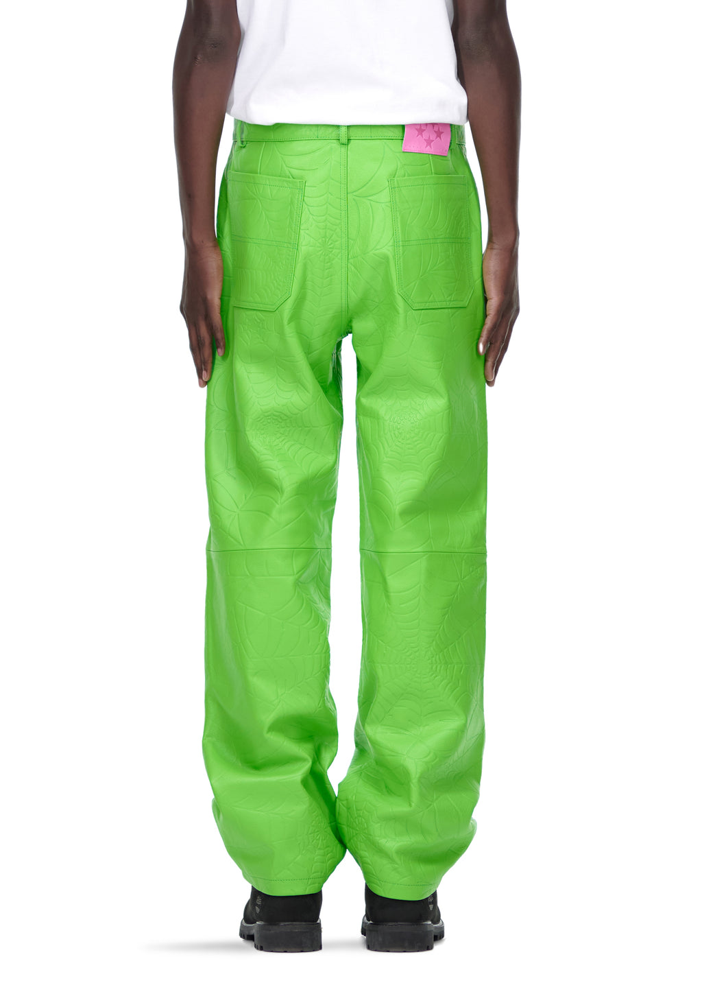 Back view of male model wearing bright green debossed web leather pants with a pink suede logo patch.