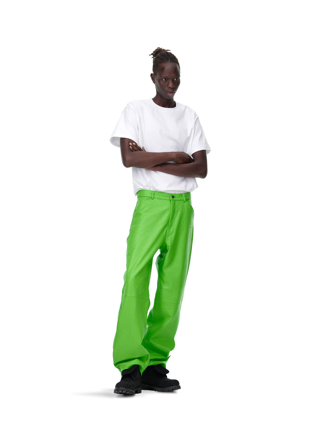 Male model in bright green debossed web leather pants, white t-shirt, and black shoes.