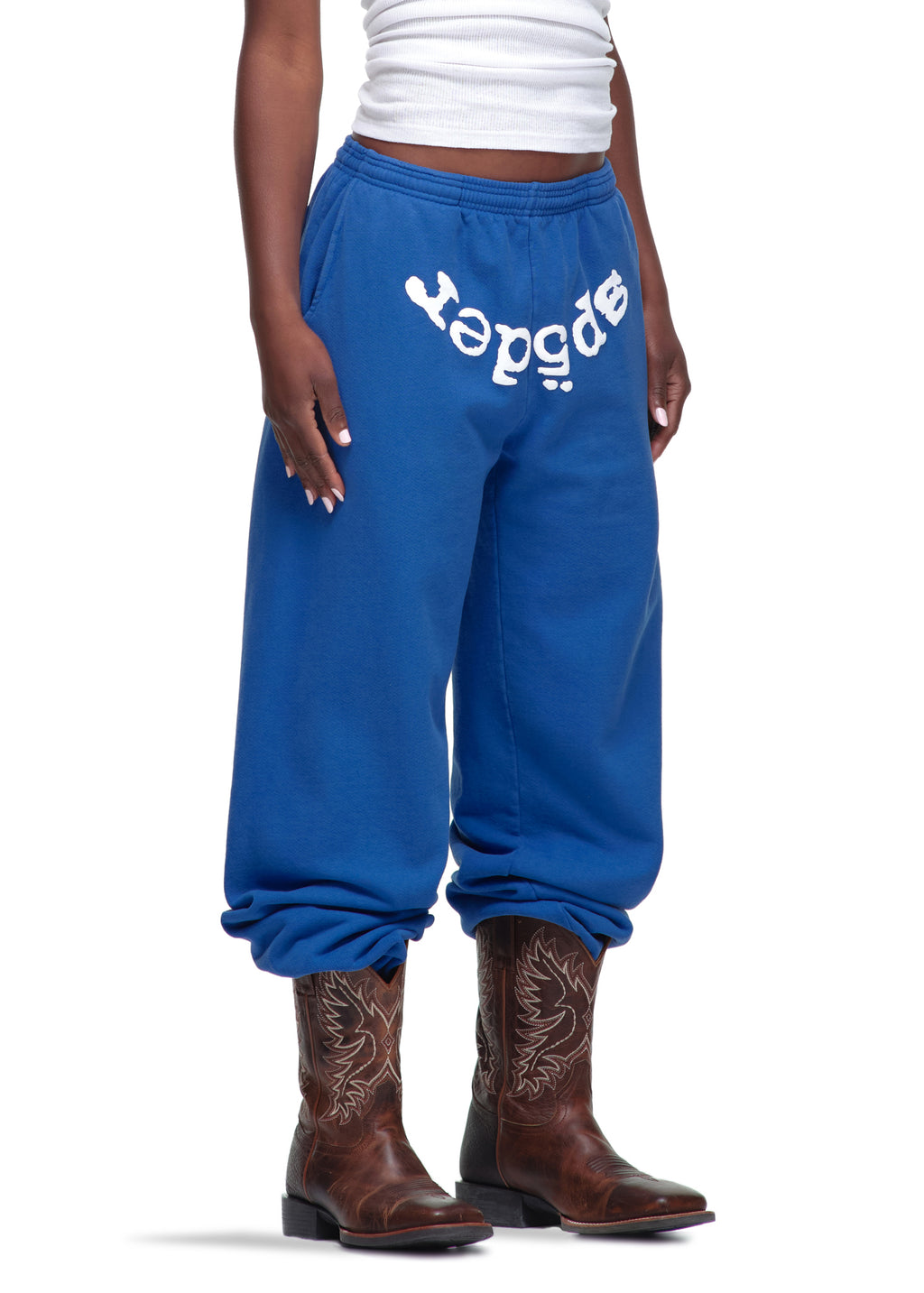 Blue 23oz fleece Legacy Sweatpants with white "sp5der" puff print, worn with cowboy boots.