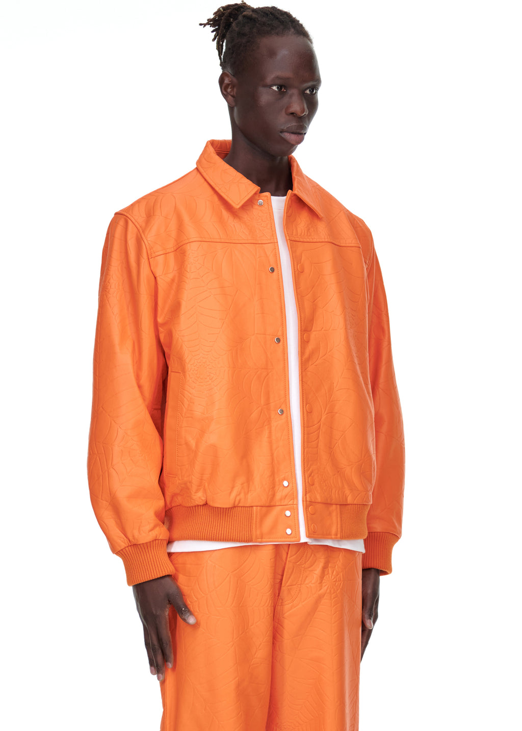 Male model in orange debossed web leather jacket with spread collar, press-stud closure, and ribbed trim.