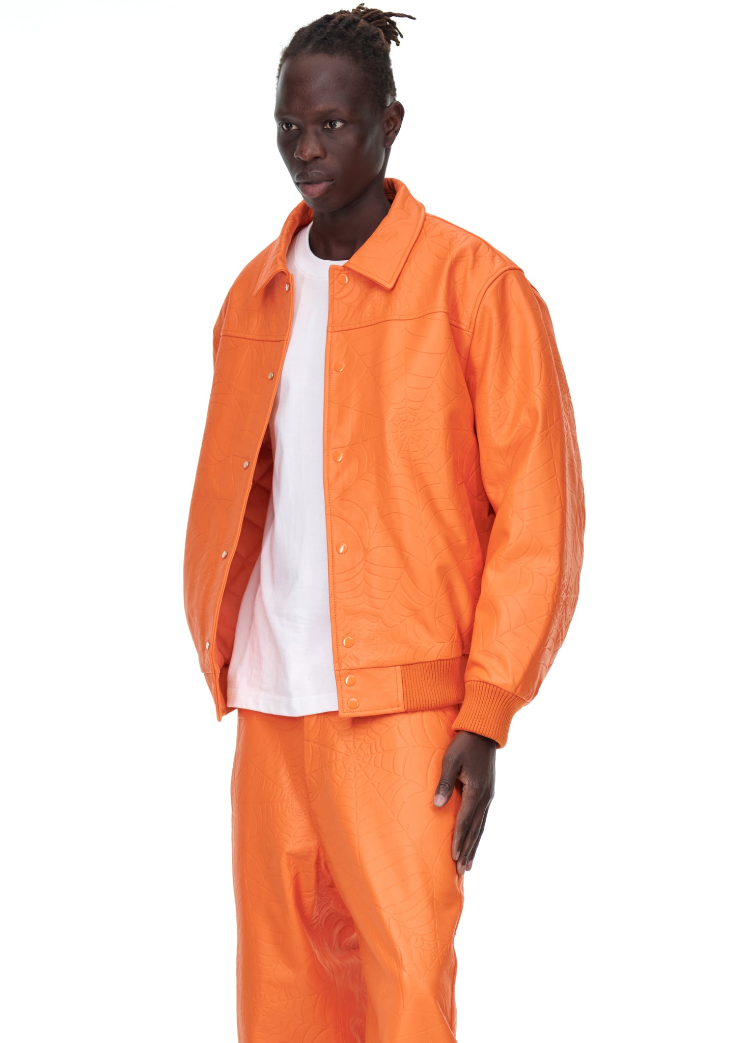 Male model in an orange debossed web cowskin leather jacket with a white tee and matching pants.
