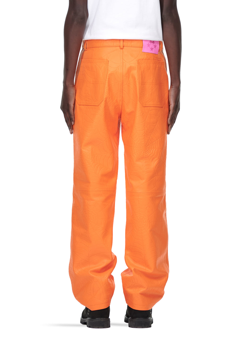 Back view of orange cowskin leather pants with debossed web design and pink suede logo patch.
