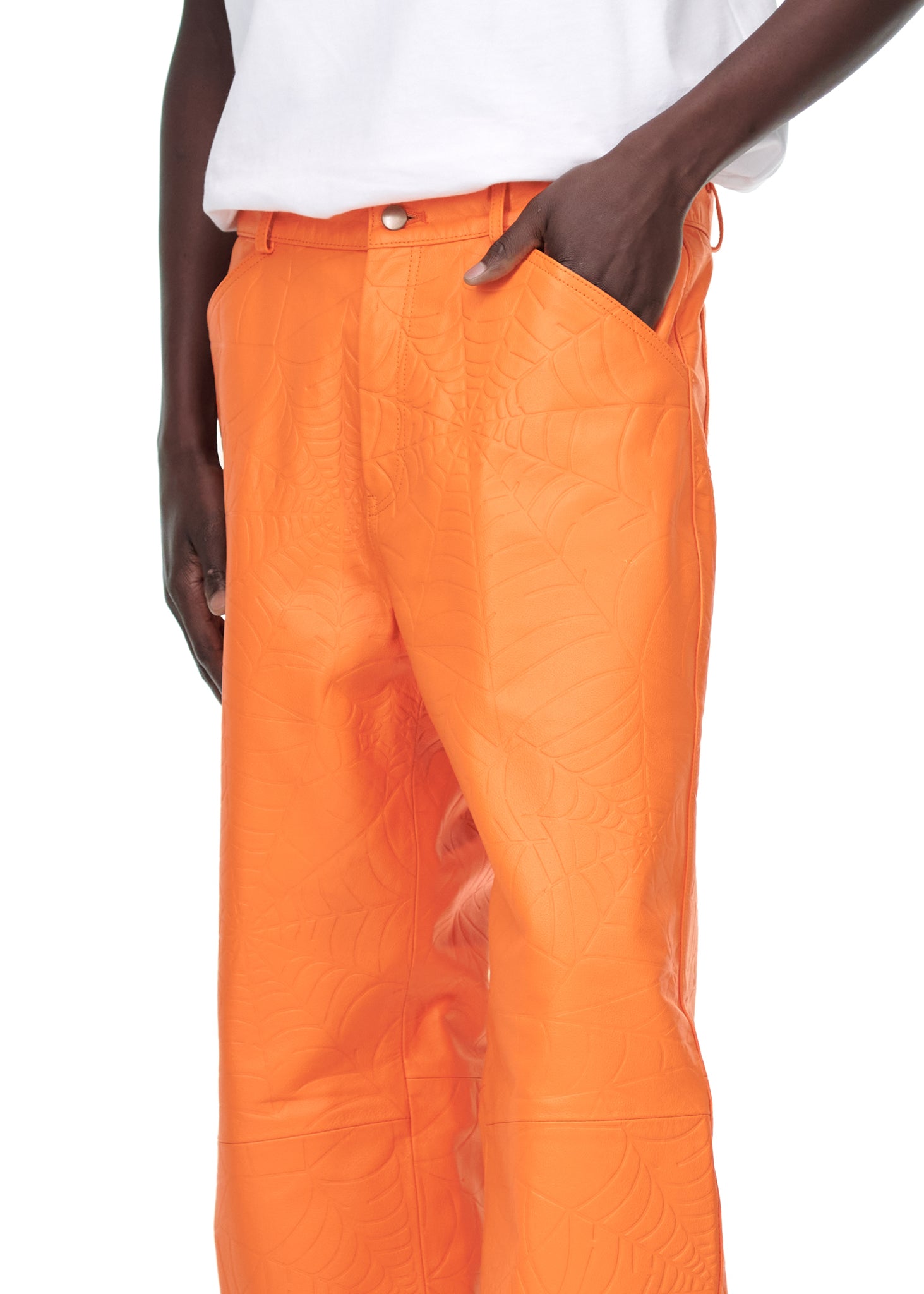 Orange cowskin leather pants with debossed web design, worn by a male model.