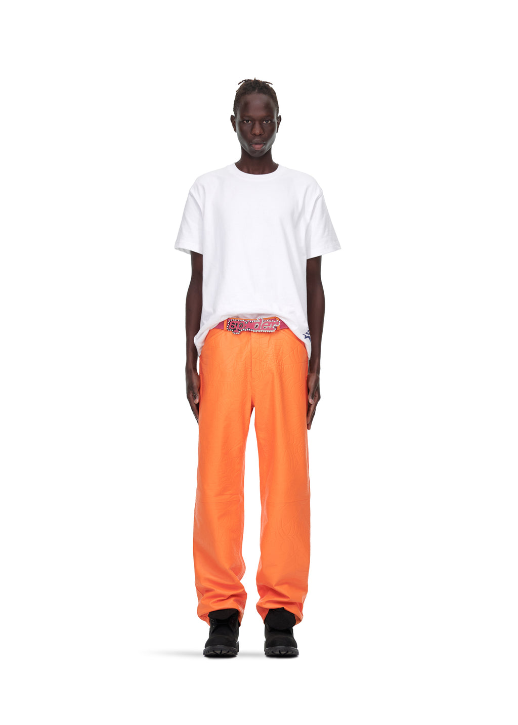 Male model in white t-shirt and orange debossed web cowskin leather pants with pink suede logo.