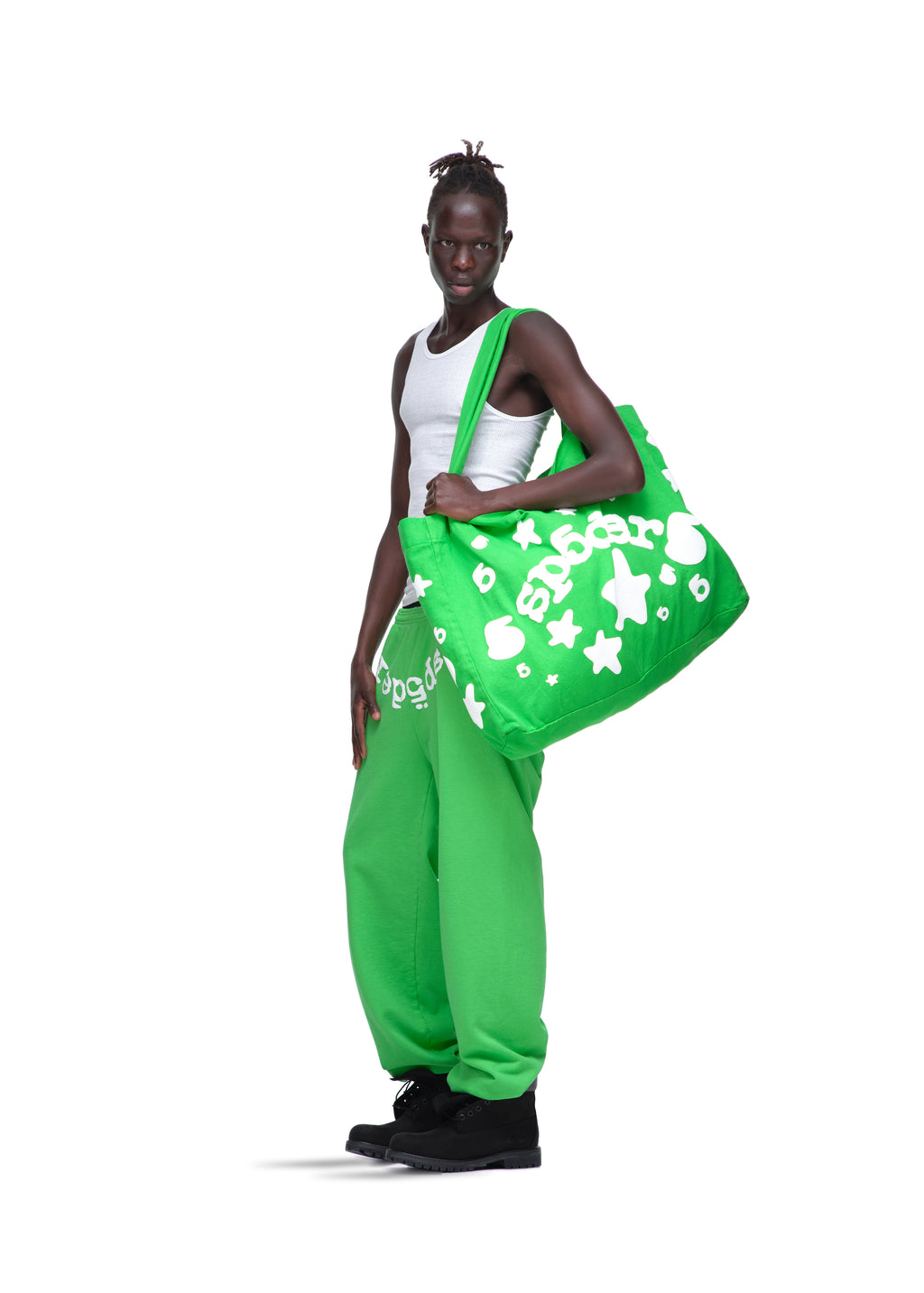 Model holding a large bright green Beluga Tote bag with white puff print stars and text.