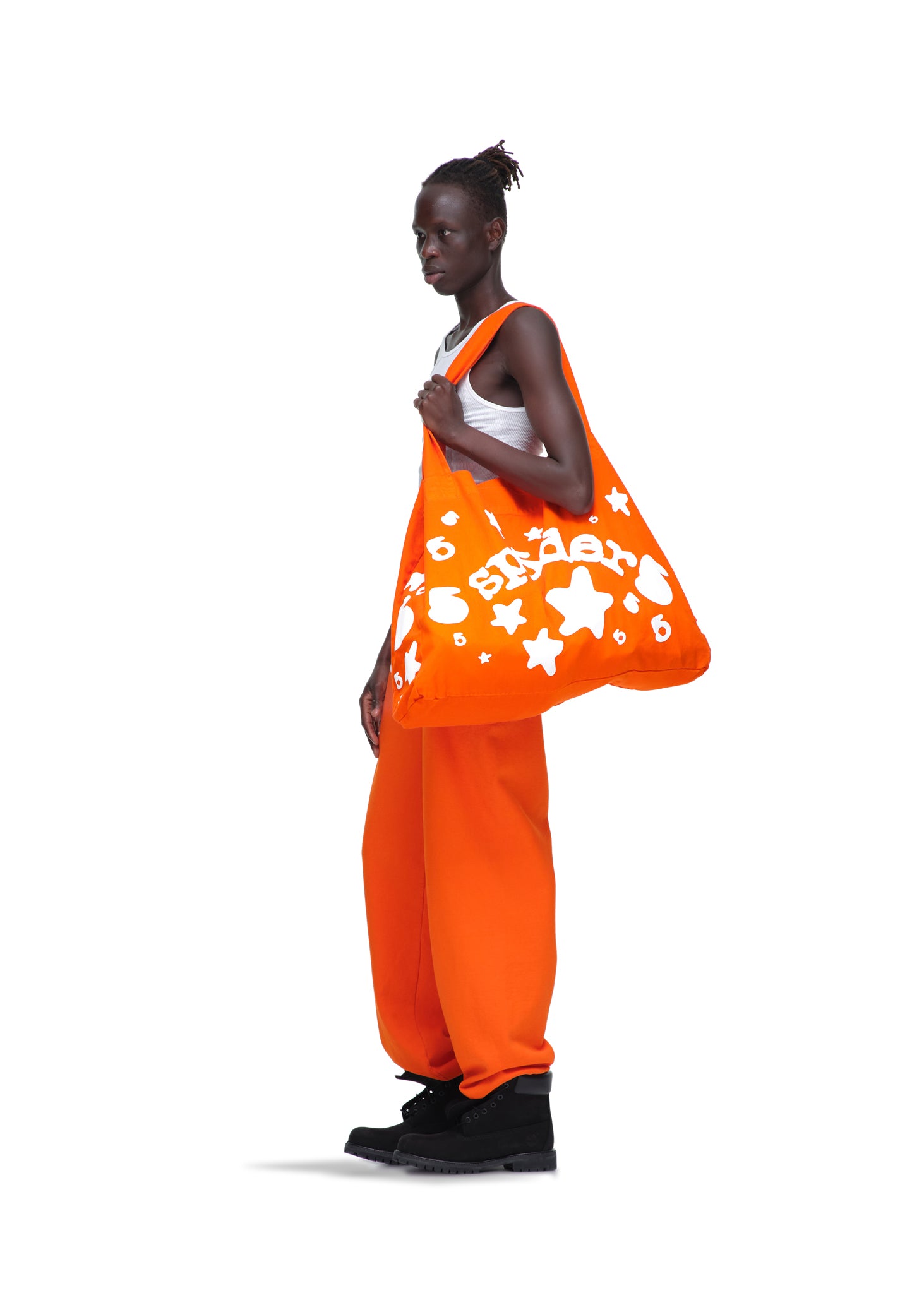 Model holding an orange 8oz twill Beluga tote bag with white star and text print.