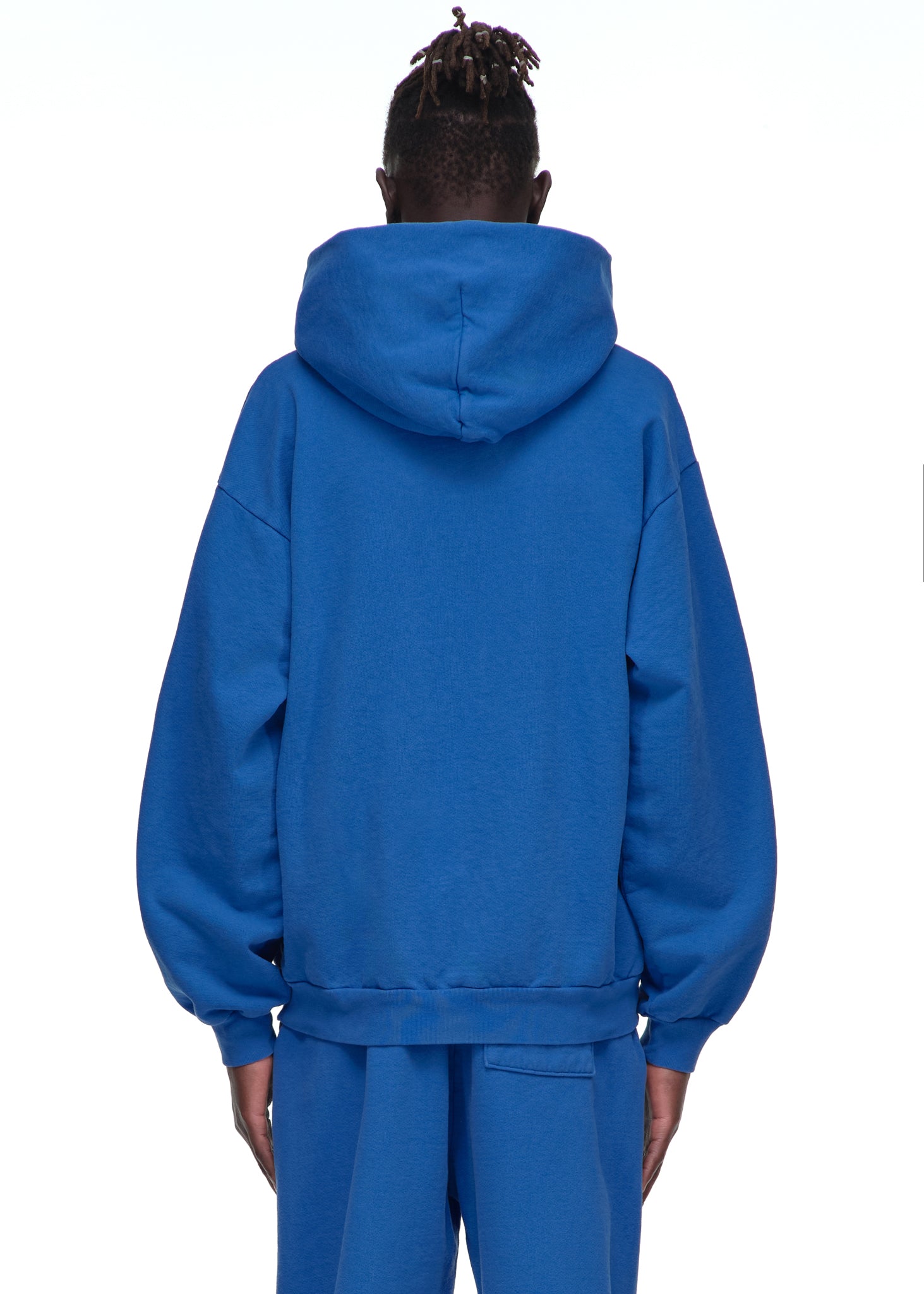 Back of a male model wearing a royal blue Legacy Hoodie and matching sweatpants.
