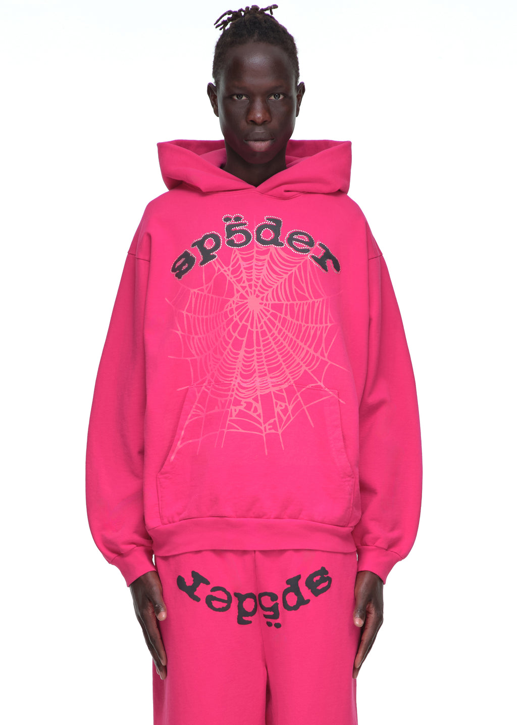 Male model in a bright pink LEGACY HOODIE with rhinestone SP5DER text and web print.