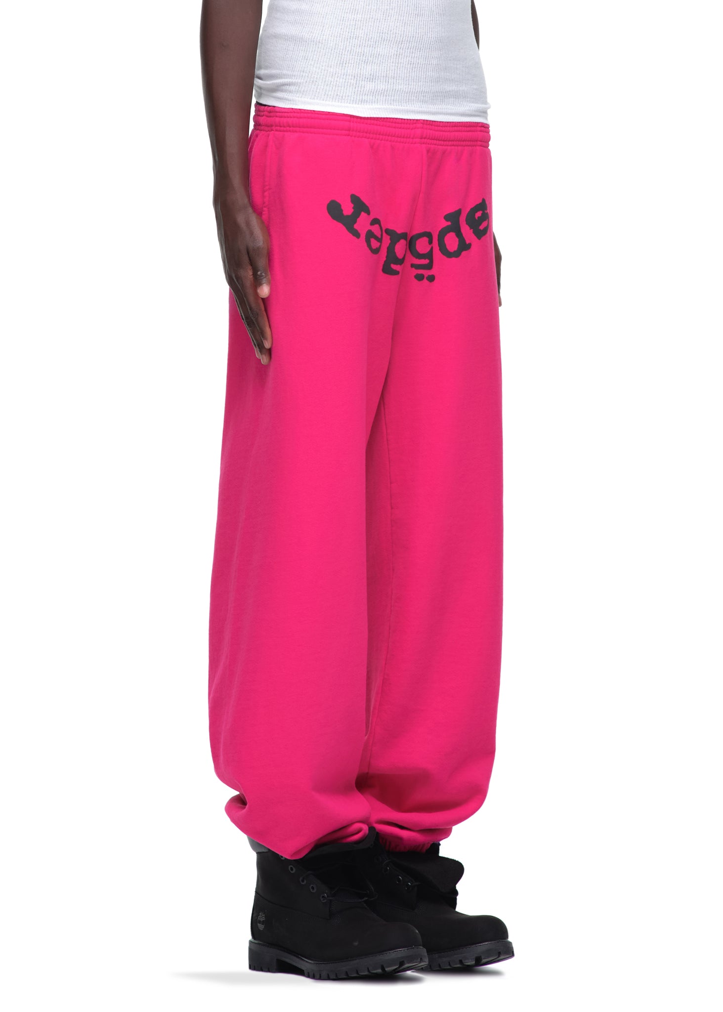 Pink 23oz fleece Legacy sweatpants with black puff print "Sp5der" text, worn with black boots.