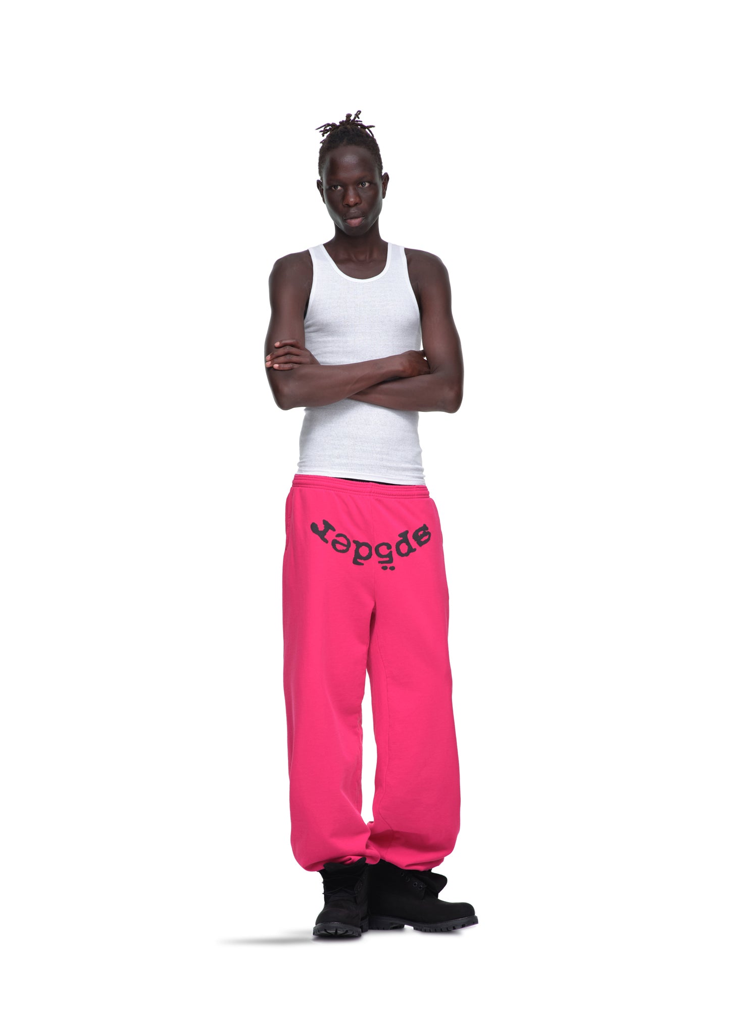 Male model in white tank top and pink LEGACY SWEATPANT with black "sp5der" puff print, black boots.