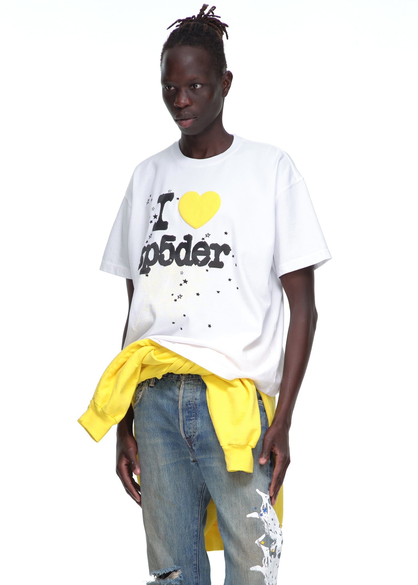 Male model in white 14oz cotton Souvenir Tee with yellow heart graphic, blue jeans, and yellow sweatshirt.