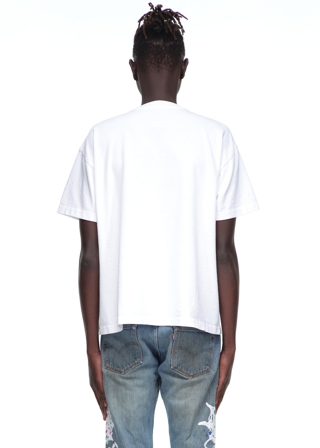 Back view of male model wearing a white 14oz cotton standard fit Souvenir Tee and distressed jeans.