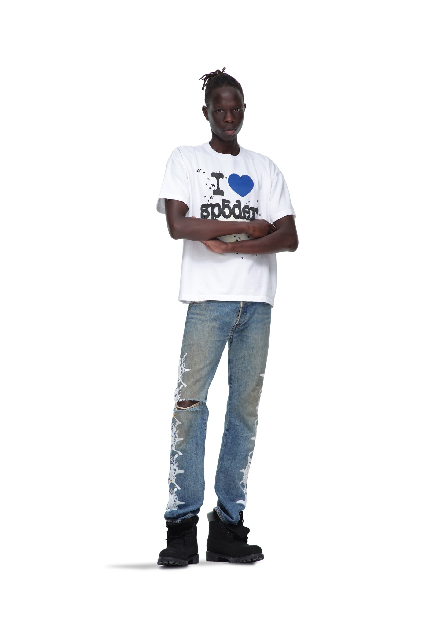 Male model in white 14oz cotton "I heart Sp5der" graphic tee, distressed blue jeans, and black boots.