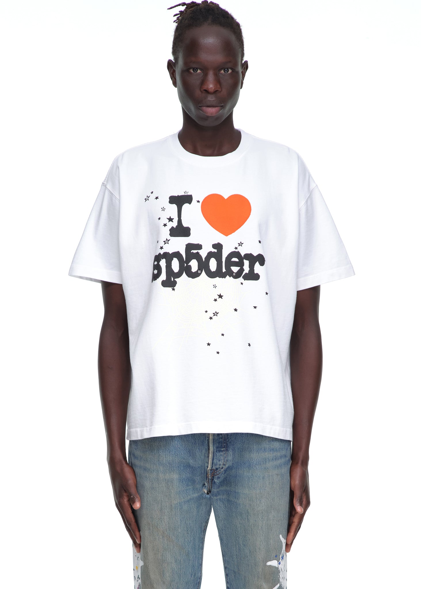 Male model in white 14oz cotton Souvenir Tee with "I ❤️ sp5der" graphic and stars, paired with jeans.