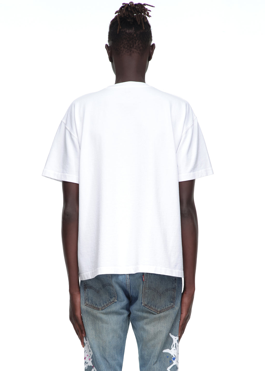 Male model in standard fit white 14oz cotton Souvenir Tee and distressed jeans, back view.