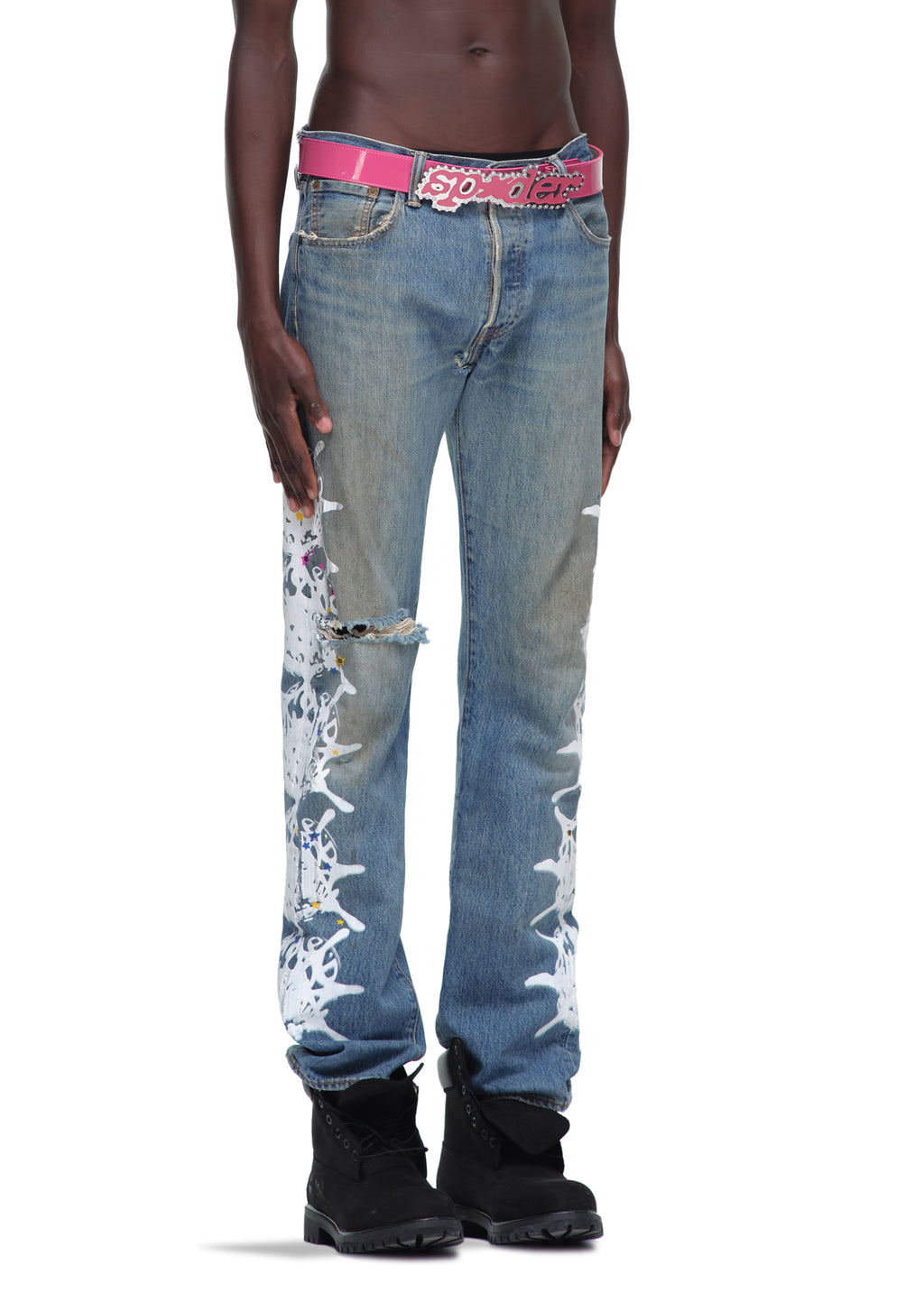 P*NK V2 BELT: Pink patent leather belt with rhinestone SP5DER buckle, worn with distressed jeans.