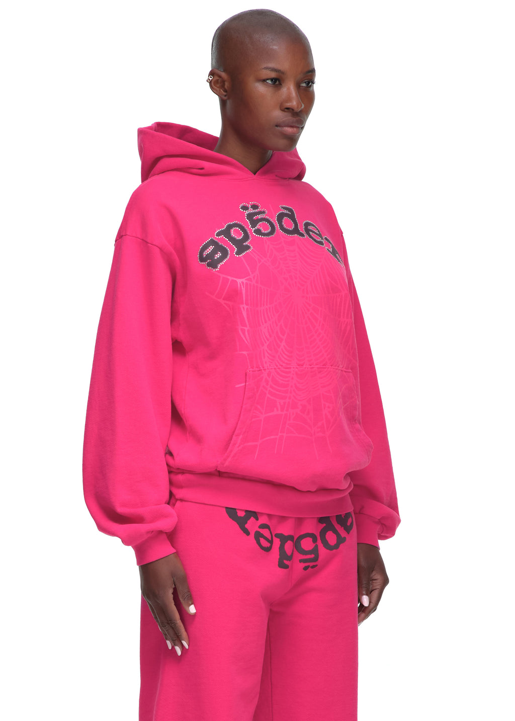 Pink Legacy Hoodie with rhinestone "SP5DER" text and web print, worn by a female model.