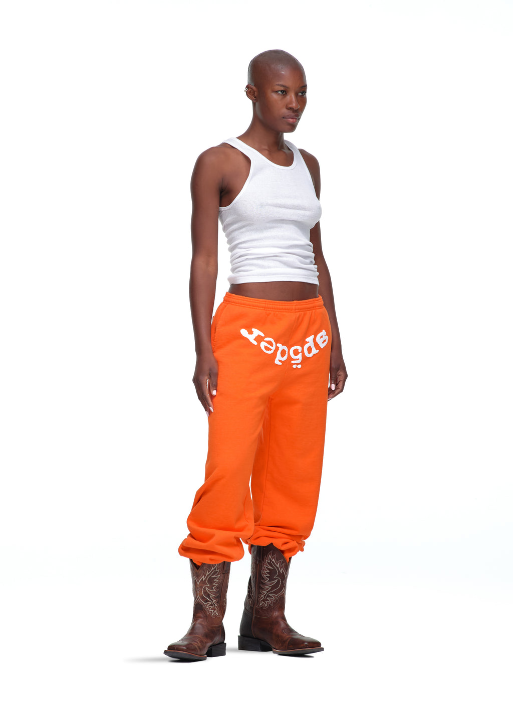 Orange 23oz fleece Legacy Sweatpants with white puff/discharge print "sp5der" text, worn by a model.