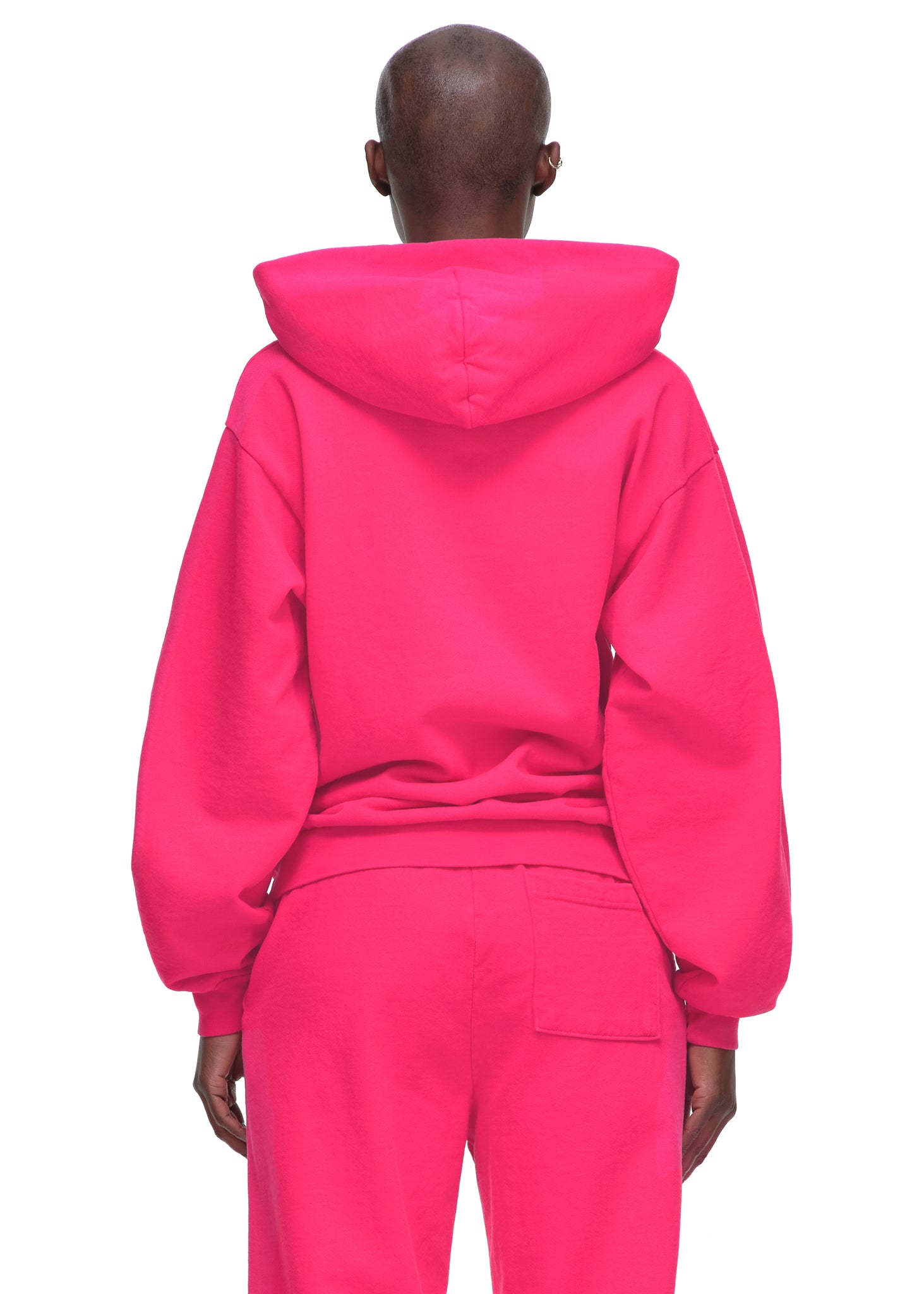 Back view of a person wearing a bright pink 23oz fleece Legacy Hoodie and matching sweatpants.
