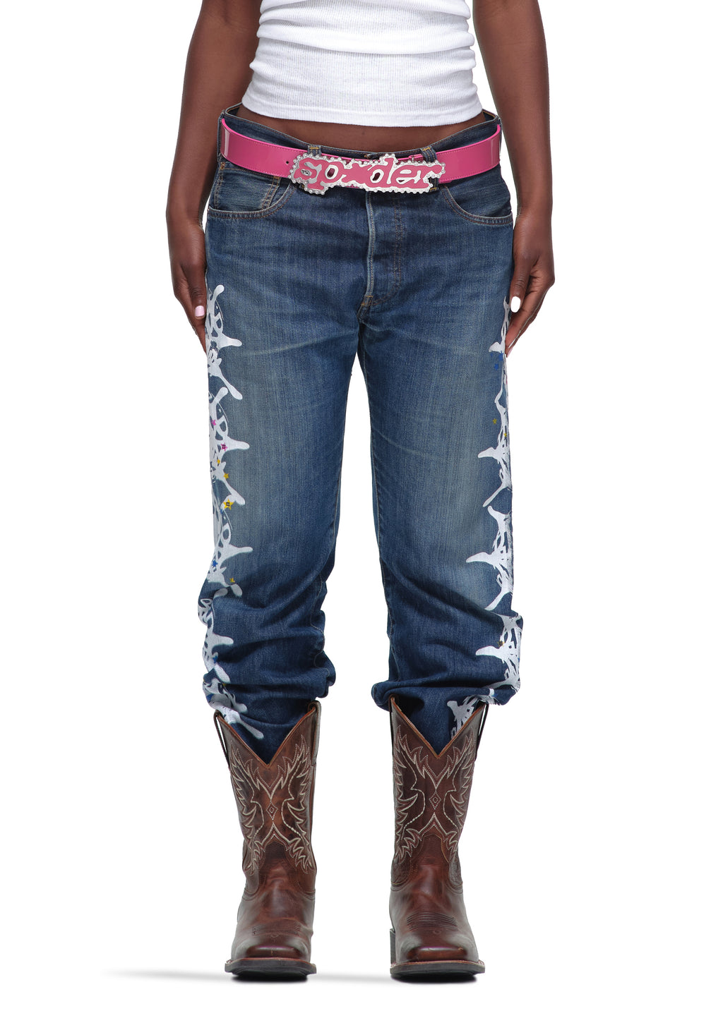 P*NK V2 BELT: Pink patent leather belt with rhinestone "SP5DER" buckle, worn with jeans and cowboy boots.