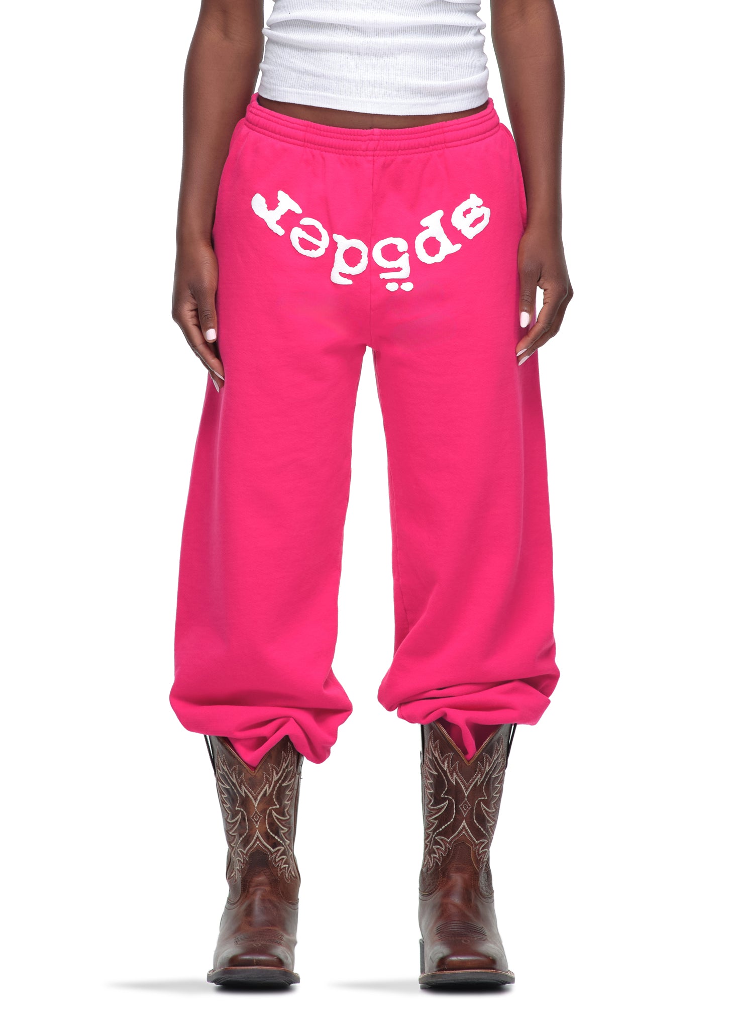 Pink 23oz fleece Legacy Sweatpants with white puff print "SP5DER" text, worn with cowboy boots.