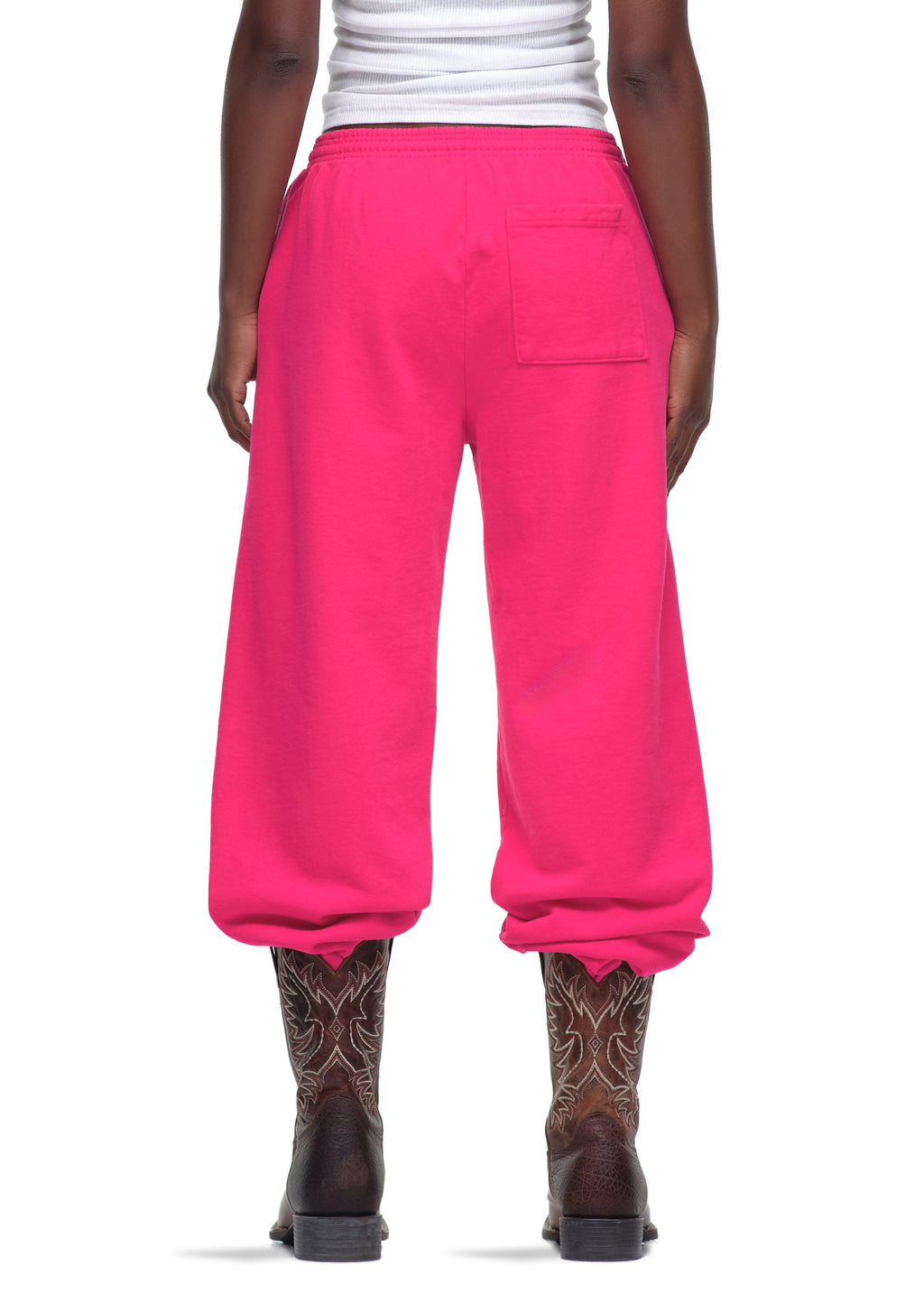 Back view of bright pink 23oz fleece Legacy Sweatpants with a back pocket, worn with cowboy boots.