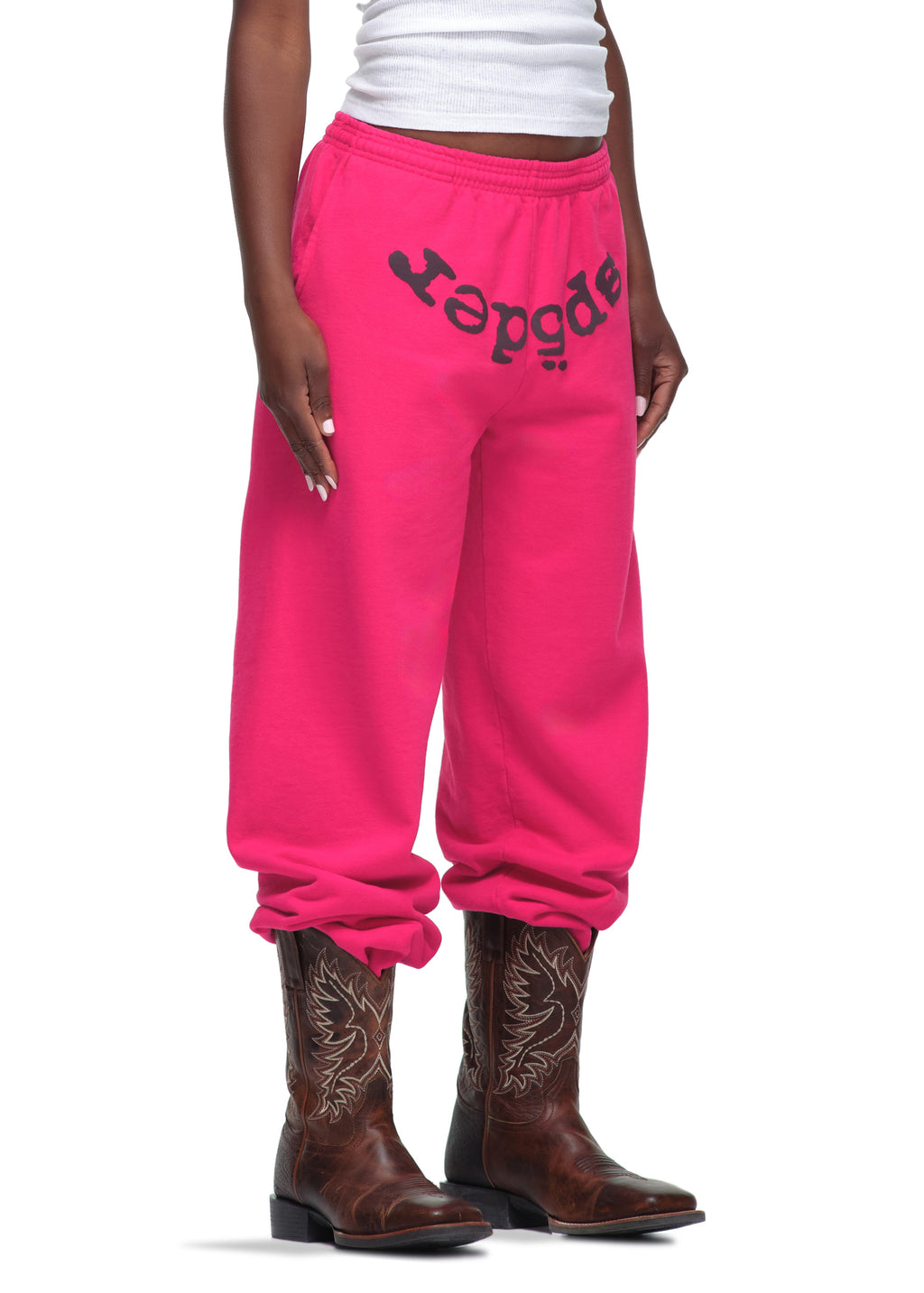 Hot pink LEGACY SWEATPANT with black "Sp5der" puff print, worn with cowboy boots.