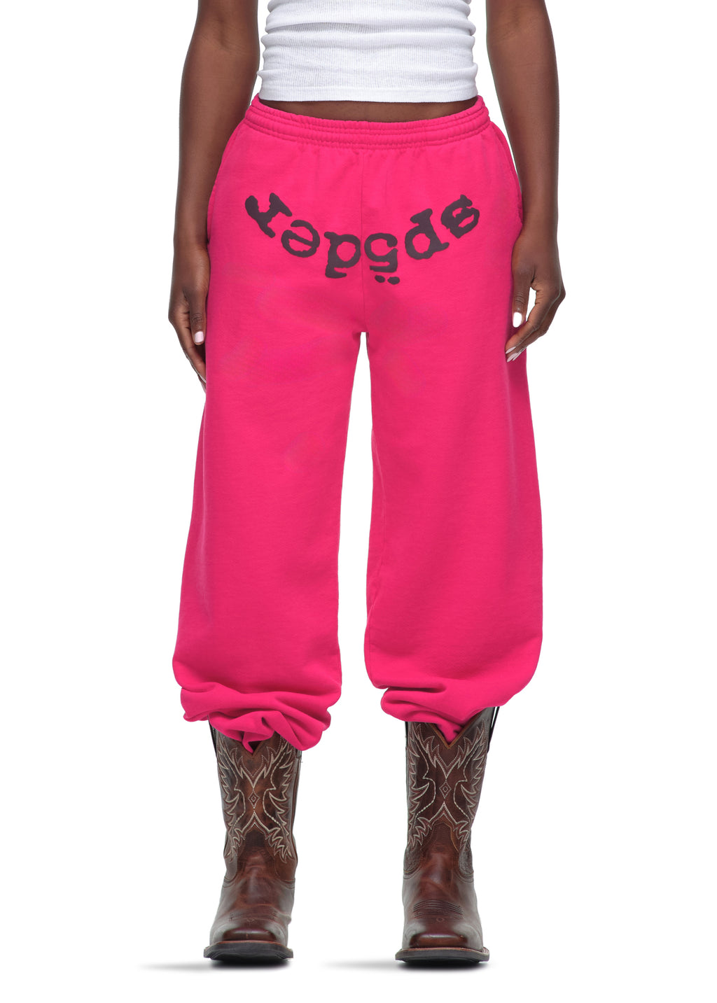 Pink LEGACY SWEATPANT with black "sp5der" puff print, made from 23oz fleece, worn with cowboy boots.