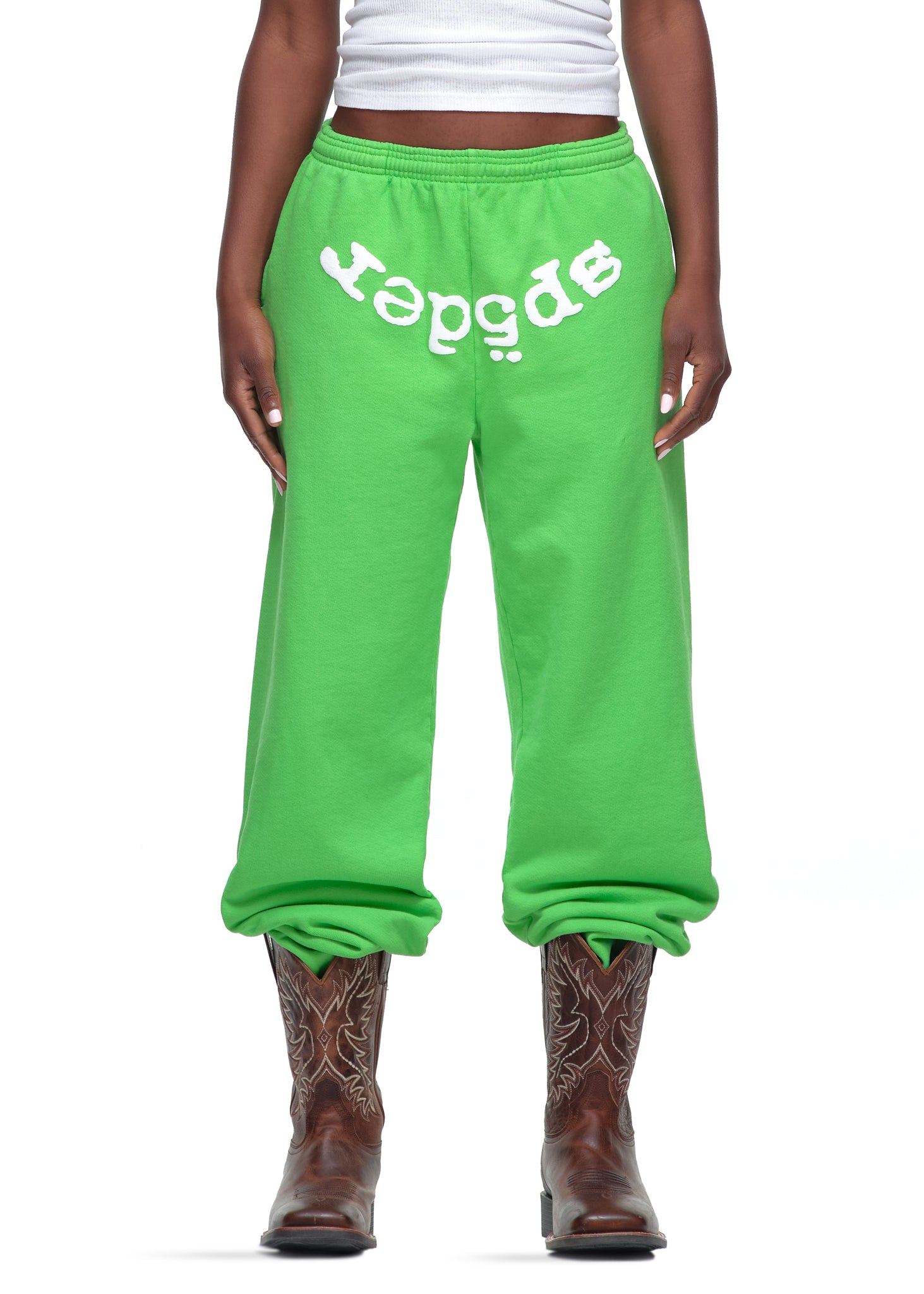 Green Legacy Sweatpants with white "SP5DER" puff print, worn with brown cowboy boots.