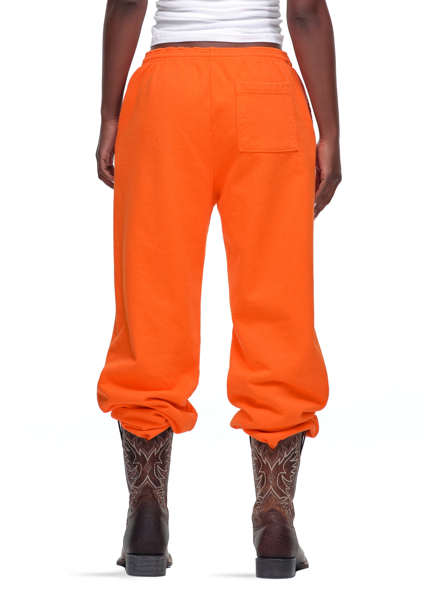 Orange 23oz fleece Legacy Sweatpants with a back pocket, worn with cowboy boots.
