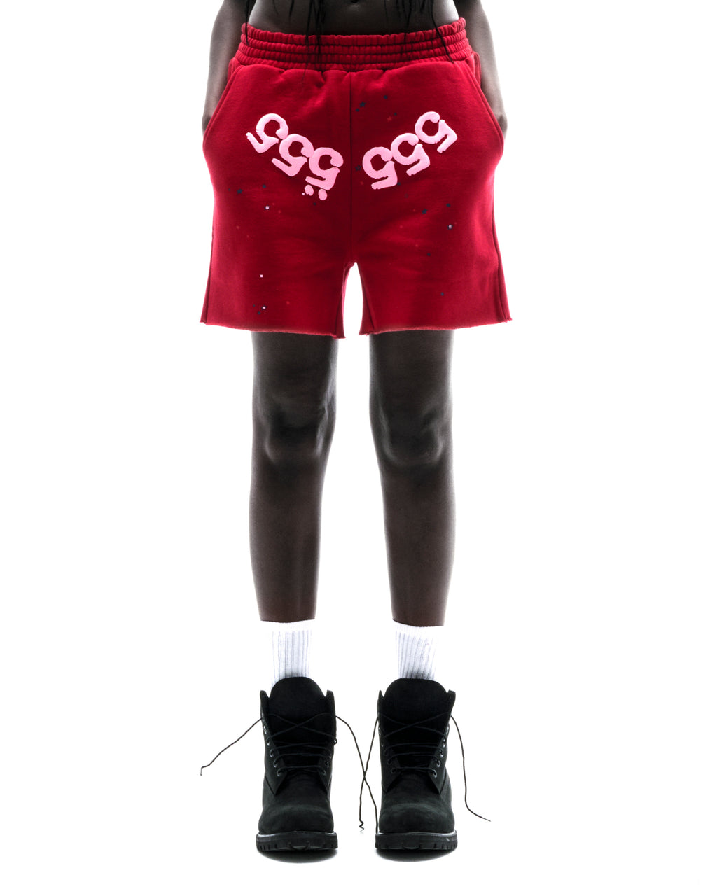 Model wearing red 100% cotton fleece shorts with pink "555" angel numbers and scattered stars.