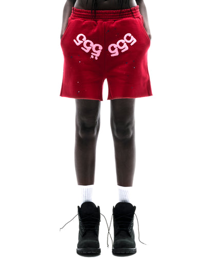 Model wearing red 100% cotton fleece shorts with pink "555" angel numbers and scattered stars.