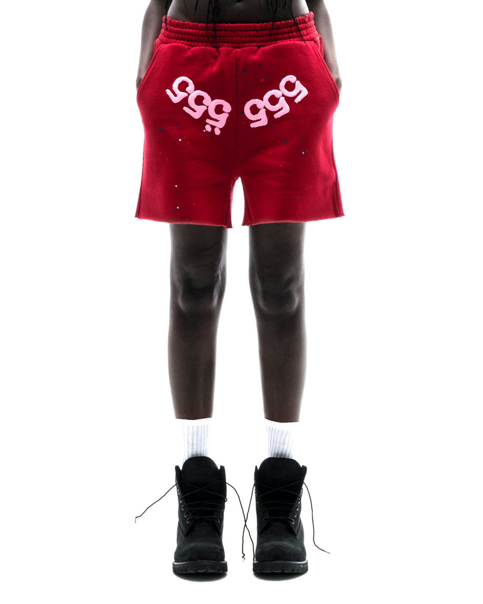 Model wearing red 100% cotton fleece shorts with pink "555" angel numbers and scattered stars.